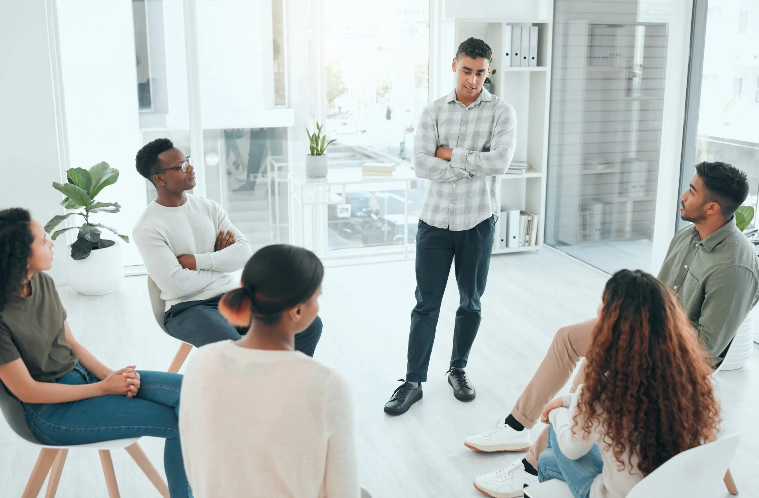 A man leading a group discussion in a bright office space.
