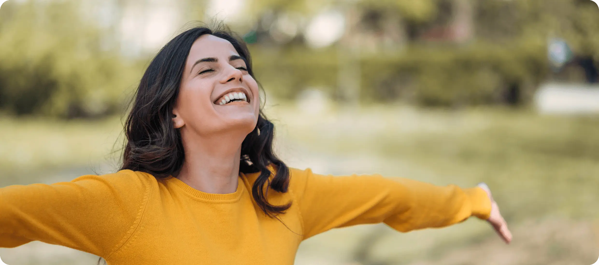 Smiling woman in yellow sweater outdoors.