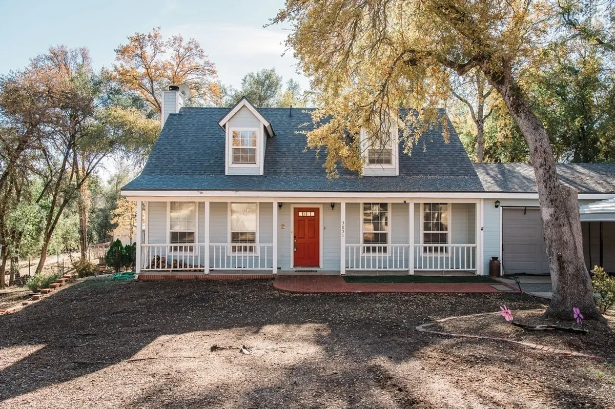 Charming house with porch and autumn trees.